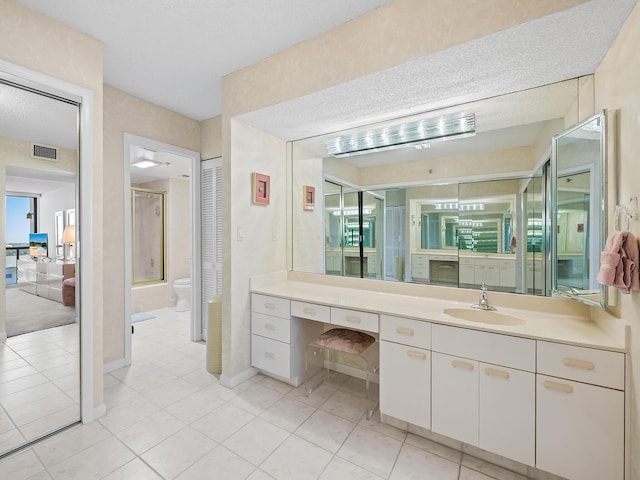 bathroom featuring a shower with shower door, tile patterned floors, toilet, and vanity