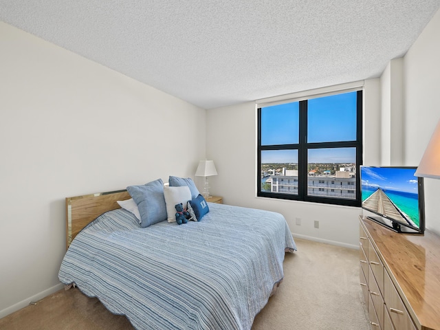 bedroom featuring light colored carpet and a textured ceiling