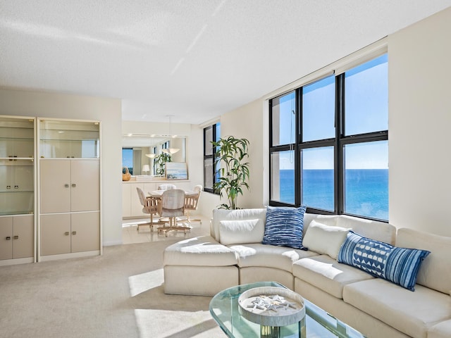 living room with carpet flooring, floor to ceiling windows, a water view, and a textured ceiling