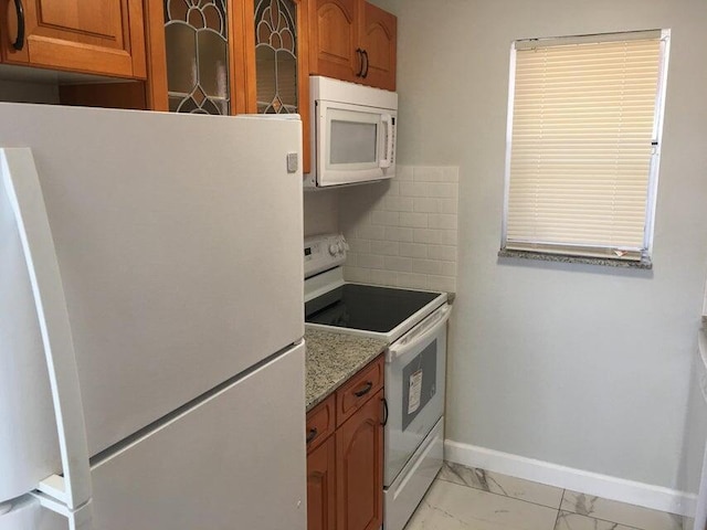 kitchen featuring light stone countertops, white appliances, and backsplash