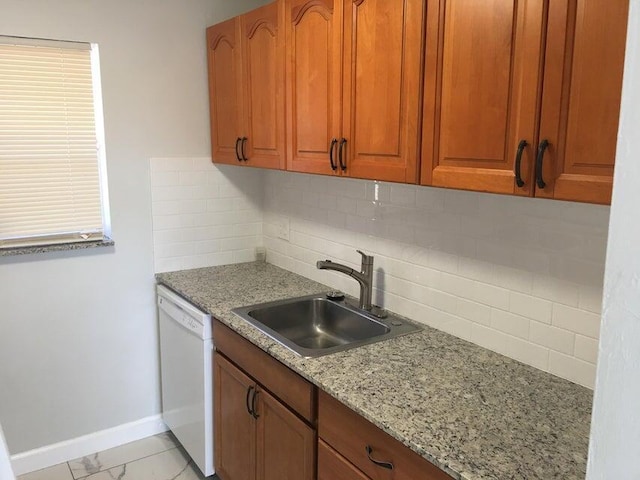 kitchen featuring backsplash, light stone counters, sink, and white dishwasher