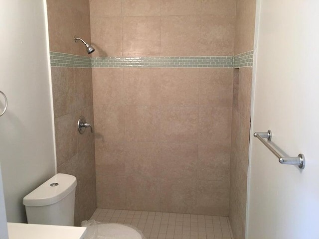 bathroom with a tile shower and toilet