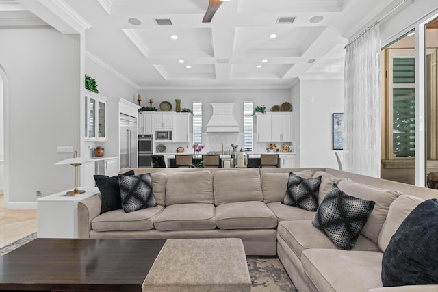 living room with beam ceiling, coffered ceiling, and ornamental molding