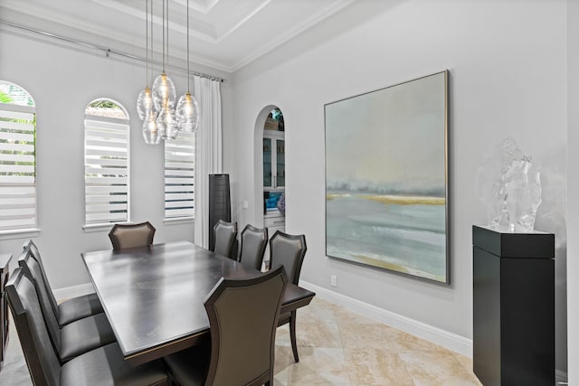 dining space with a raised ceiling, ornamental molding, light tile patterned floors, and an inviting chandelier