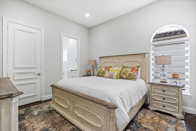 bedroom featuring connected bathroom and dark hardwood / wood-style flooring