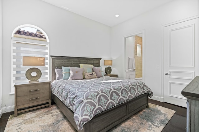 bedroom with ensuite bath and dark wood-type flooring