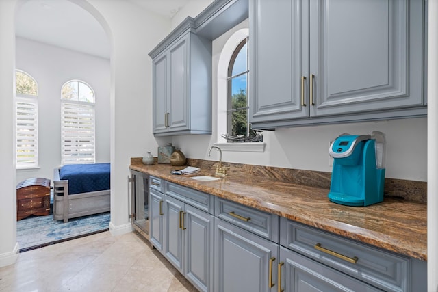 kitchen featuring sink, wine cooler, gray cabinets, dark stone countertops, and light tile patterned floors