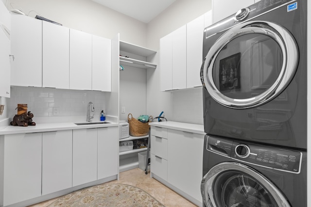 washroom featuring cabinets, sink, and stacked washer and clothes dryer