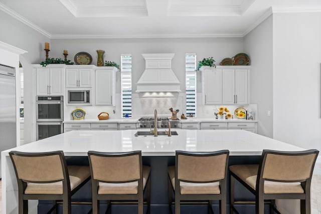 kitchen with white cabinets, built in appliances, premium range hood, and a large island