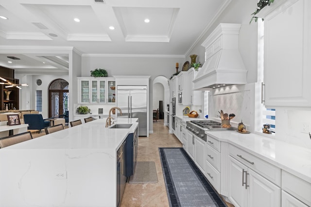 kitchen featuring a kitchen breakfast bar, backsplash, a kitchen island with sink, white cabinets, and appliances with stainless steel finishes