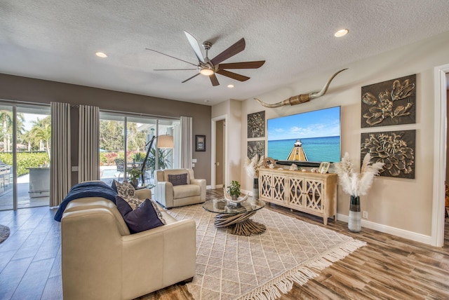 living room featuring ceiling fan, wood-type flooring, and a textured ceiling