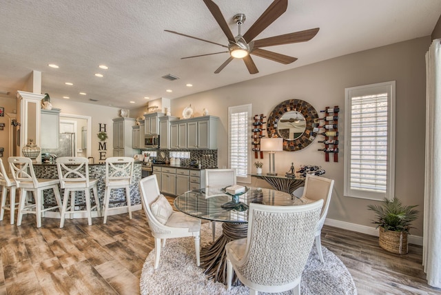 dining area with ceiling fan, wood-type flooring, and a textured ceiling