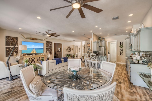 dining area with ceiling fan, hardwood / wood-style floors, and a textured ceiling