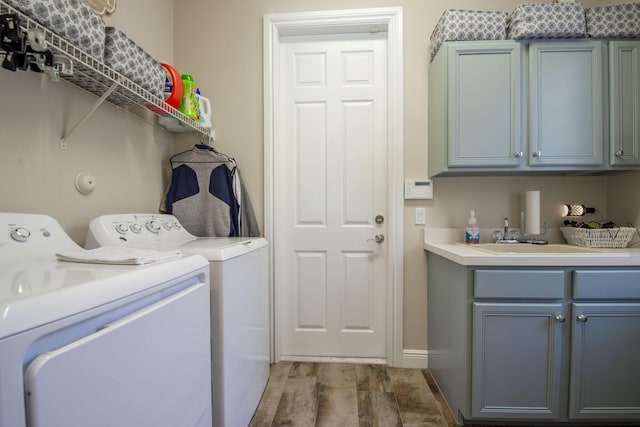 washroom with sink, cabinets, independent washer and dryer, and wood-type flooring