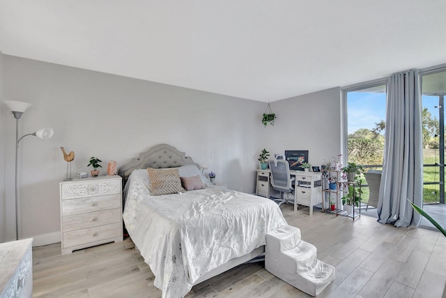 bedroom with floor to ceiling windows and light hardwood / wood-style floors