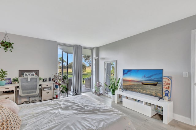 bedroom with a wall of windows, access to exterior, and light hardwood / wood-style flooring