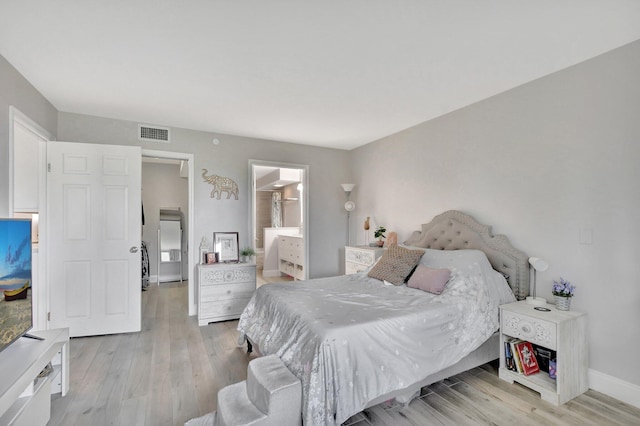 bedroom with light wood-type flooring and ensuite bathroom