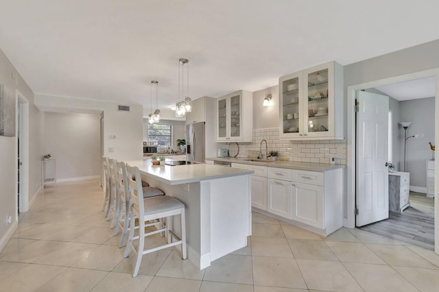 kitchen featuring sink, appliances with stainless steel finishes, white cabinets, a kitchen island, and decorative light fixtures