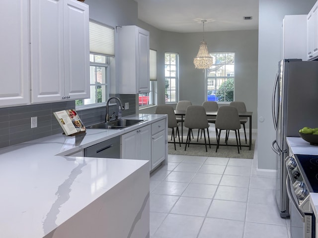 kitchen featuring backsplash, white cabinetry, stainless steel appliances, and decorative light fixtures