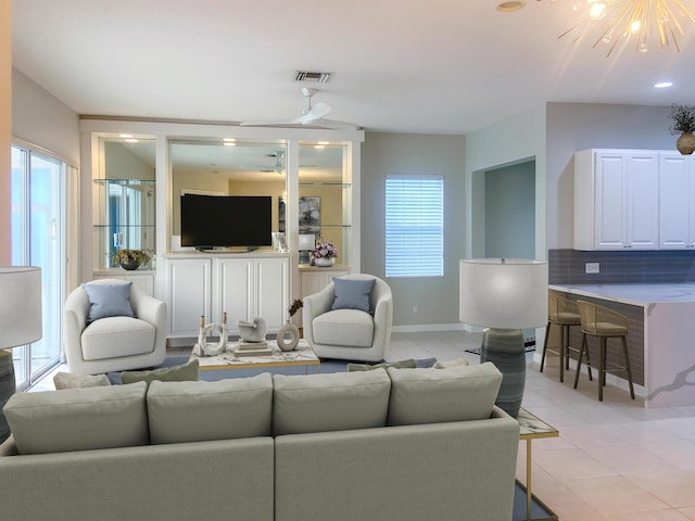 tiled living room with ceiling fan with notable chandelier