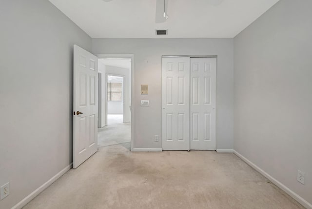 unfurnished bedroom with light colored carpet and a closet