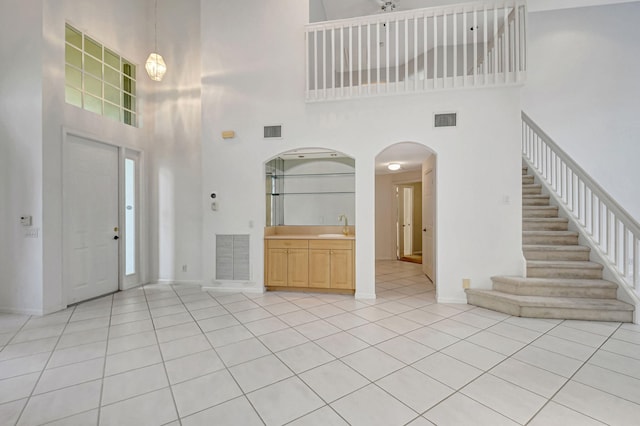 entryway featuring light tile patterned floors, a towering ceiling, and sink