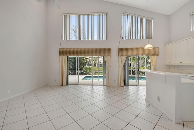 interior space featuring light tile patterned floors, a healthy amount of sunlight, and a high ceiling