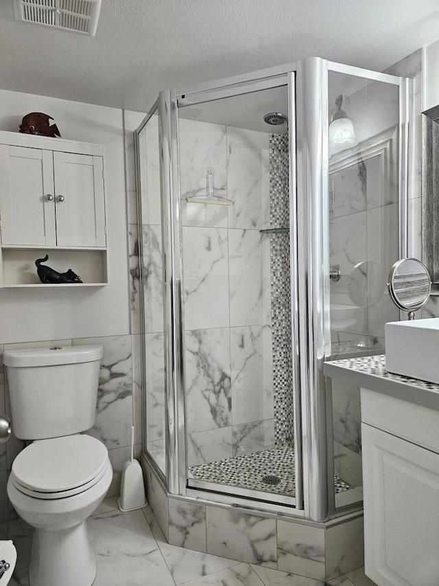 bathroom with an enclosed shower, vanity, toilet, and a textured ceiling