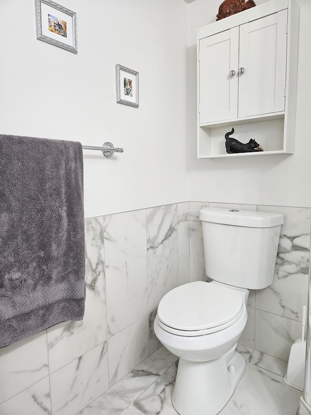 bathroom featuring tile walls and toilet