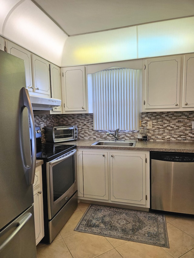 kitchen with sink, light tile patterned floors, appliances with stainless steel finishes, tasteful backsplash, and vaulted ceiling