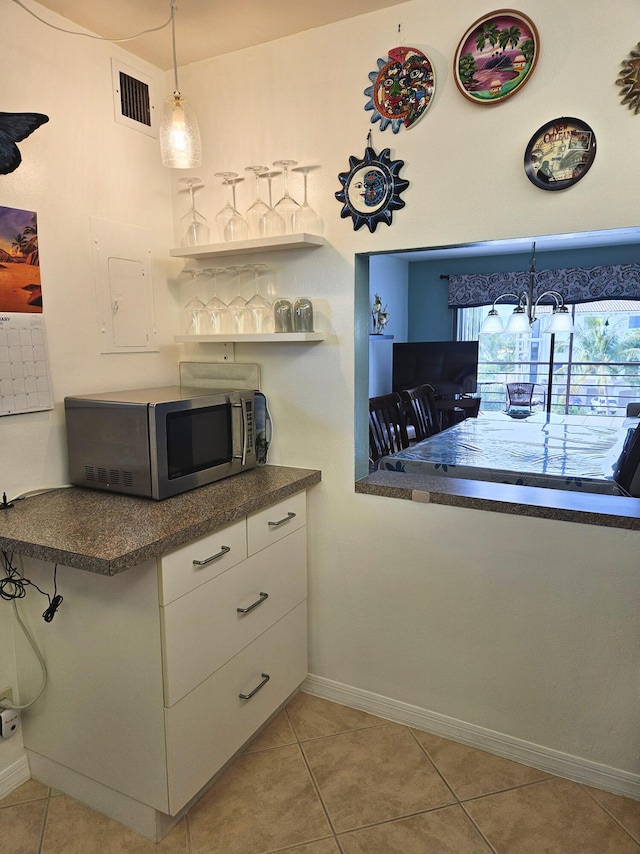 kitchen featuring white cabinetry, decorative light fixtures, a high ceiling, and light tile patterned flooring