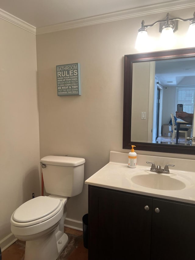 bathroom with toilet, vanity, and crown molding