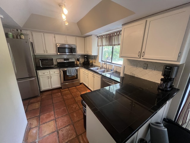 kitchen with kitchen peninsula, appliances with stainless steel finishes, decorative backsplash, white cabinets, and sink