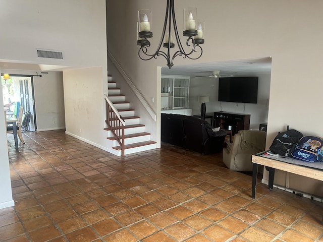 interior space with tile patterned floors, ceiling fan with notable chandelier, and a towering ceiling