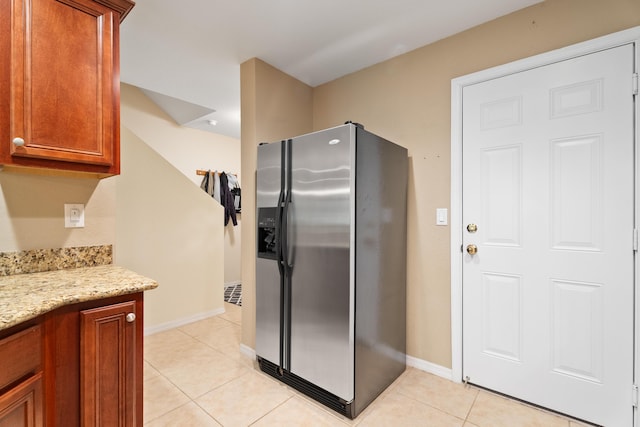 kitchen with light stone countertops, stainless steel fridge, and light tile patterned flooring