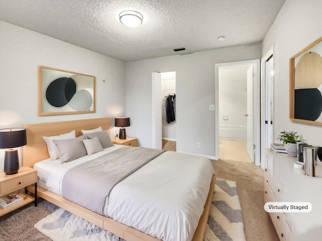 bedroom with a textured ceiling, a walk in closet, a closet, and ensuite bath