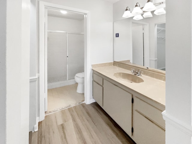 bathroom featuring toilet, vanity, a shower with shower door, and hardwood / wood-style floors