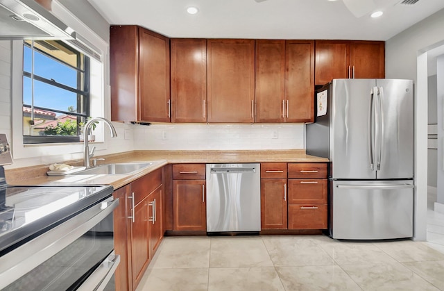 kitchen featuring appliances with stainless steel finishes, light tile patterned floors, tasteful backsplash, and sink