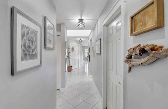 corridor with a textured ceiling and light tile patterned floors