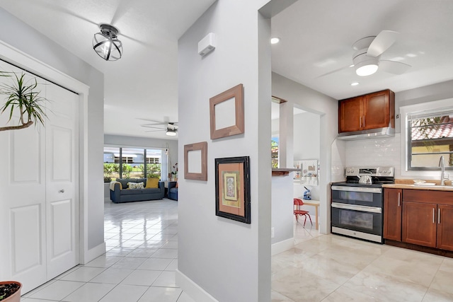 kitchen featuring sink, ceiling fan, stainless steel electric stove, and tasteful backsplash