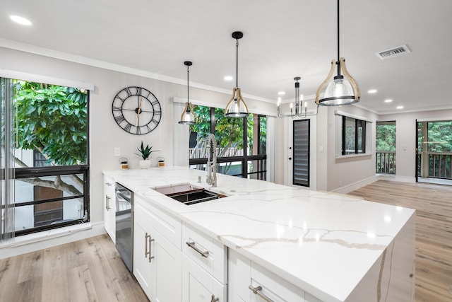 kitchen with black dishwasher, light stone counters, a healthy amount of sunlight, and sink