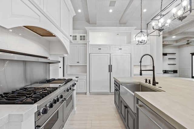 kitchen with pendant lighting, white cabinetry, high end appliances, beam ceiling, and range hood