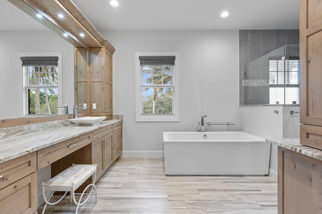 bathroom with hardwood / wood-style flooring, plenty of natural light, a bath, and vanity