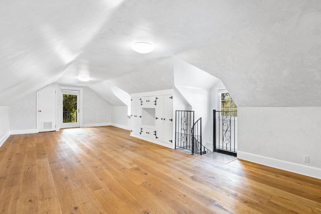 bonus room with light hardwood / wood-style floors and vaulted ceiling