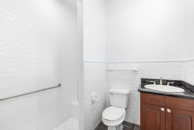 bathroom featuring toilet, vanity, tile walls, and tile patterned floors