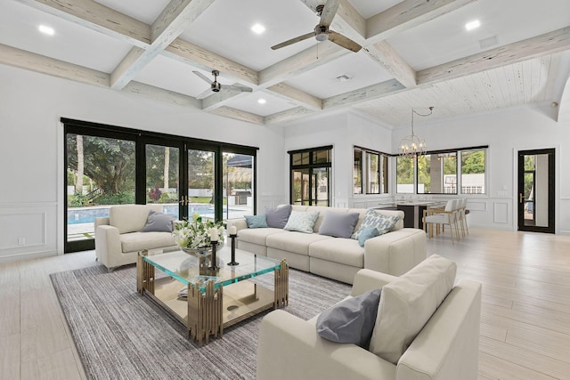 living room with ceiling fan with notable chandelier, light hardwood / wood-style flooring, beam ceiling, and french doors