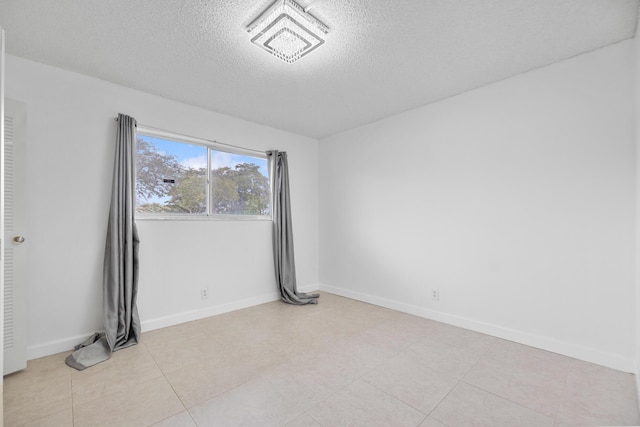 tiled empty room with a textured ceiling