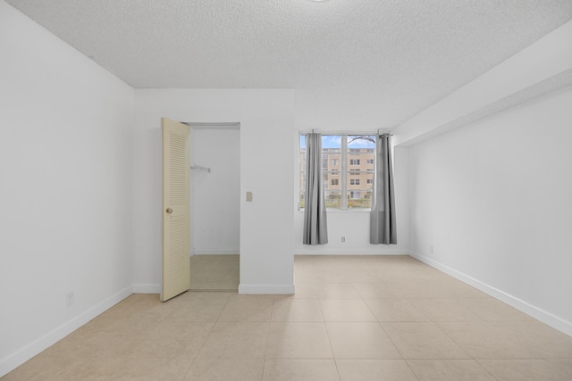 unfurnished bedroom featuring a closet, light tile patterned flooring, and a textured ceiling