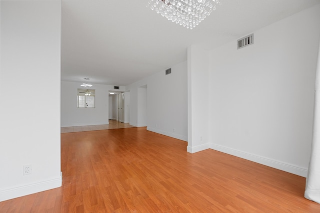 unfurnished living room featuring light hardwood / wood-style floors and a chandelier