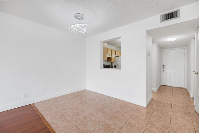 tiled empty room with a chandelier and a textured ceiling